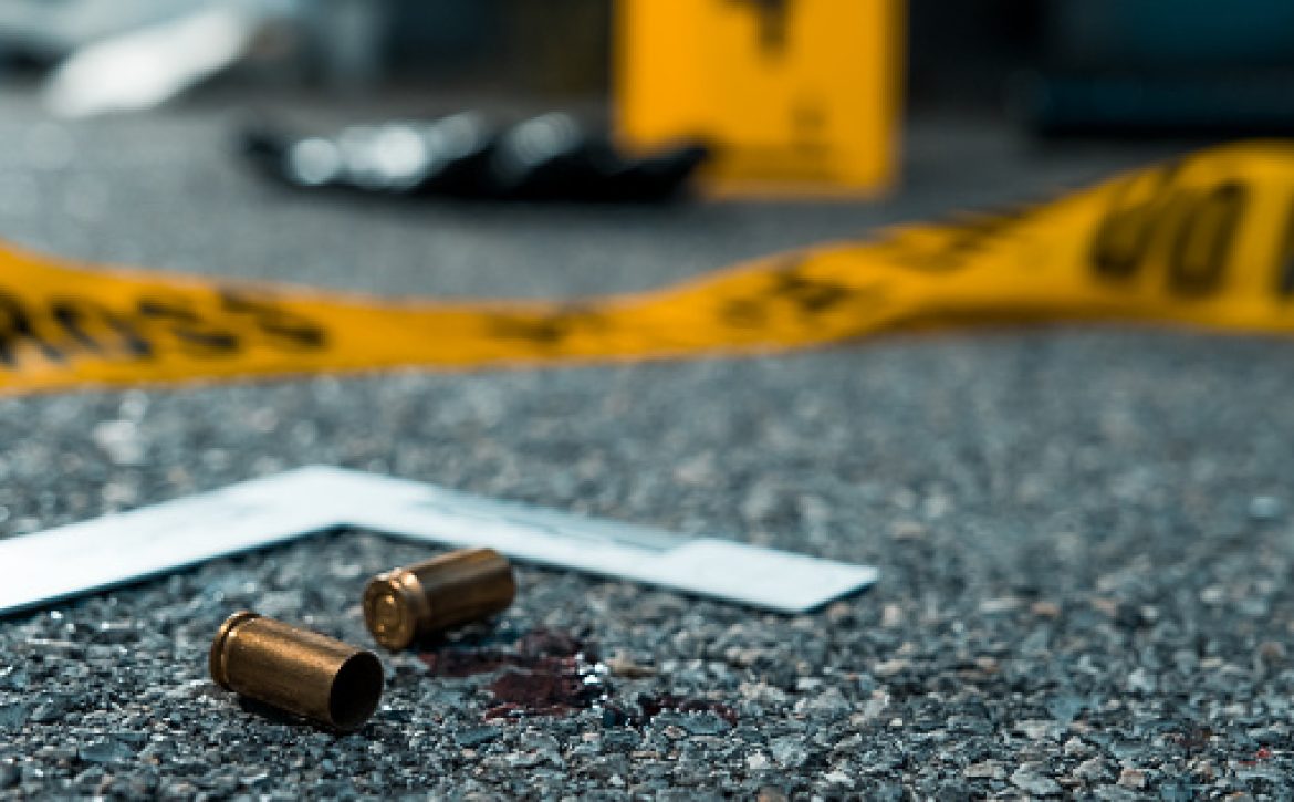 Evidence on the floor at the night shooting crime scene. Bullets, ruller, gun.