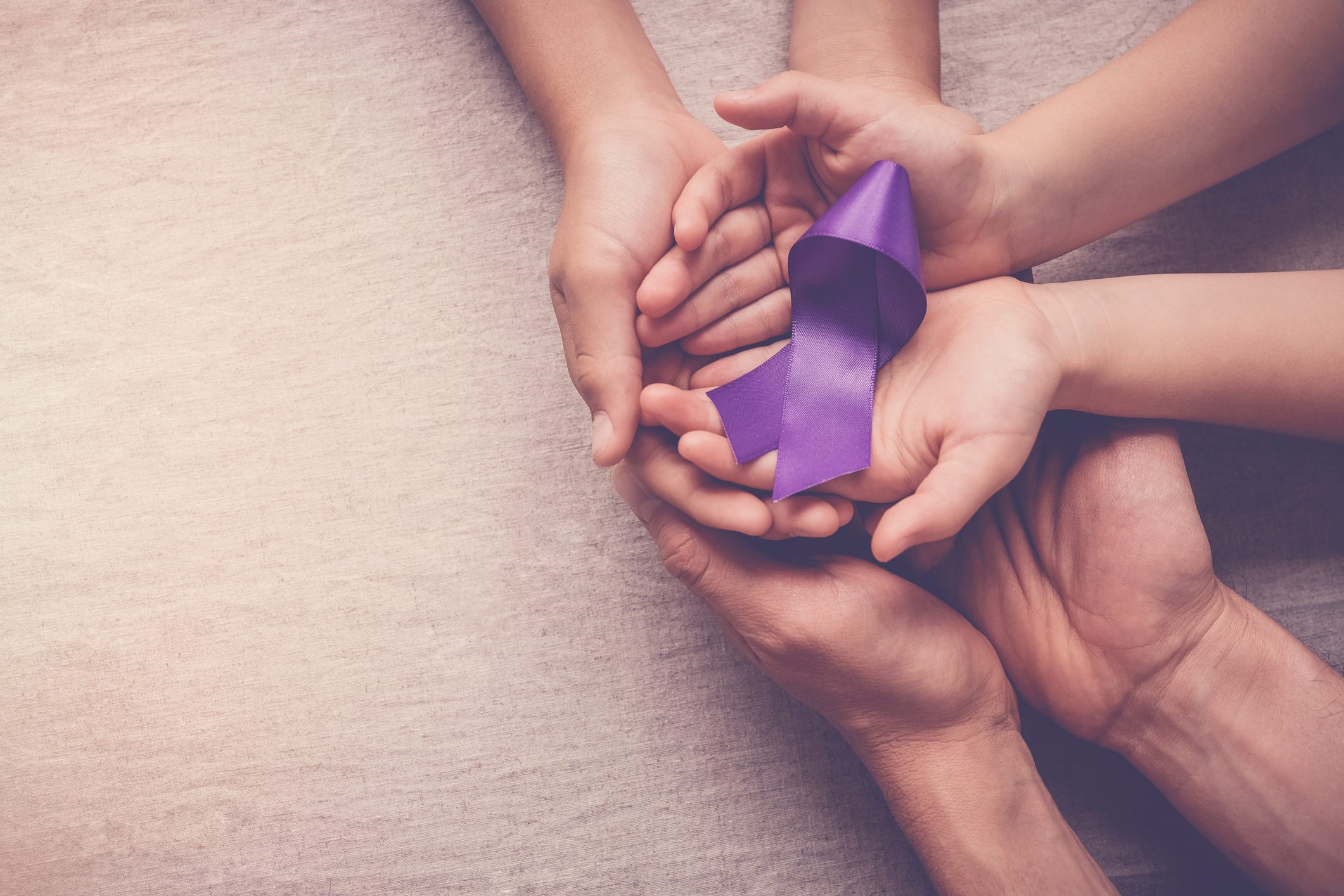 Adult and child hands holding purple ribbon, Alzheimer’s disease, Pancreatic cancer, Epilepsy awareness, world cancer day